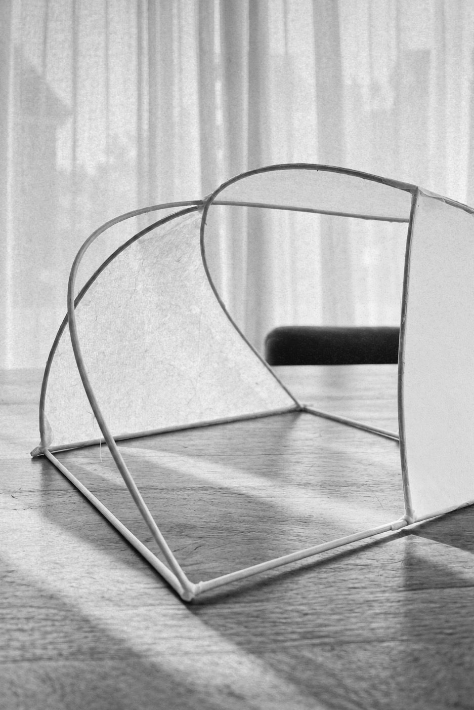 Houten lampframe op tafel voor een raam met vitrage